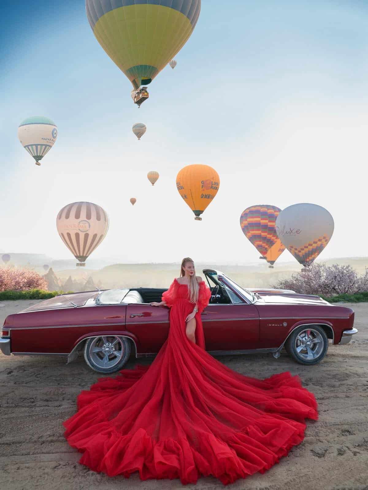 Flying dress photoshoot with a classic car and hot air balloons in Cappadocia
